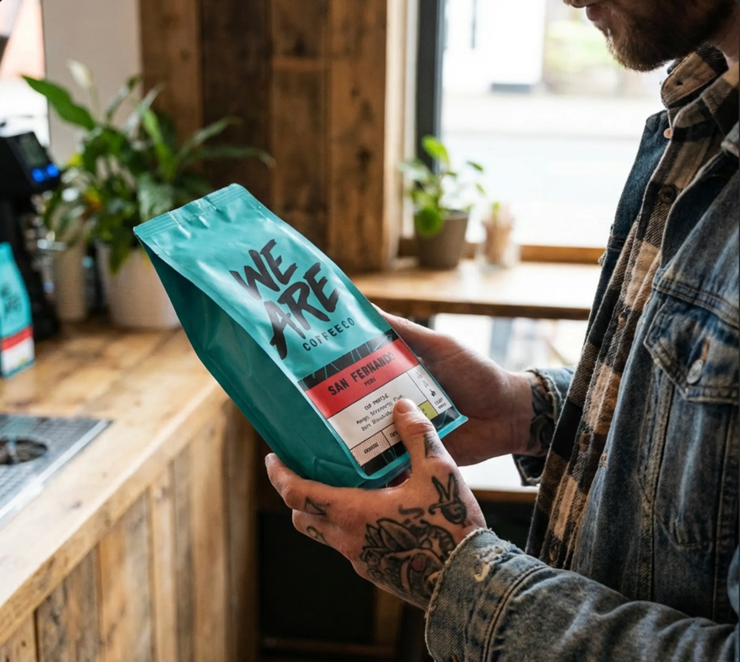 Hand holding a We Are Coffee Co bag in a bright cafe