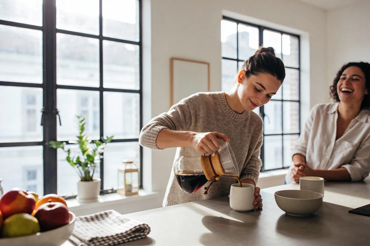 Two friends sharing freshly brewed coffee at a kitchen table